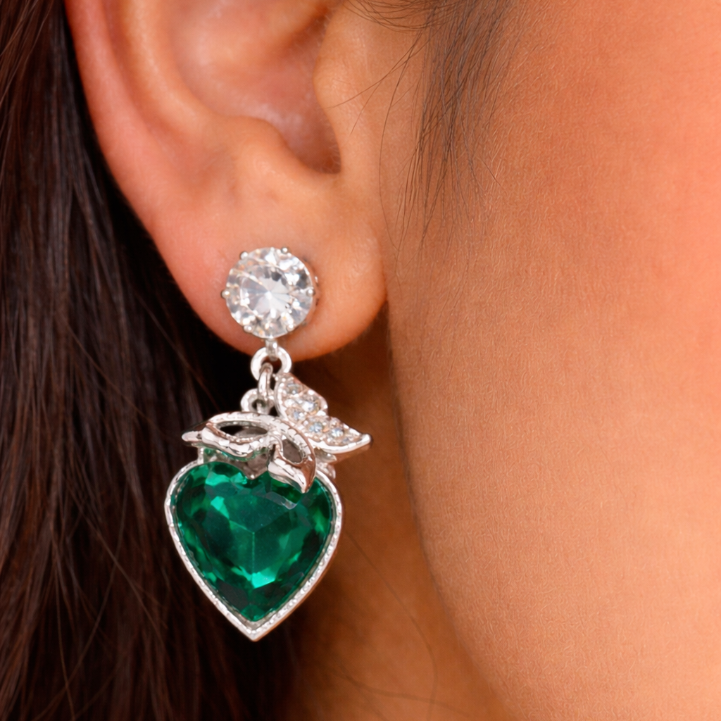 Close-up of an earring with a green heart-shaped gemstone and silver details.