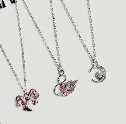 Three necklaces with pink pendants on a white background